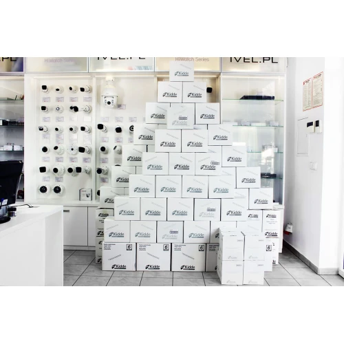 Czujnik czadu tlenku węgla i dymu Kidde 10SCO w białej obudowie z wyświetlaczem LCD i przyciskiem testowym na środku. Urządzenie posiada otwory wentylacyjne po bokach oraz wskaźnik LED na górze.