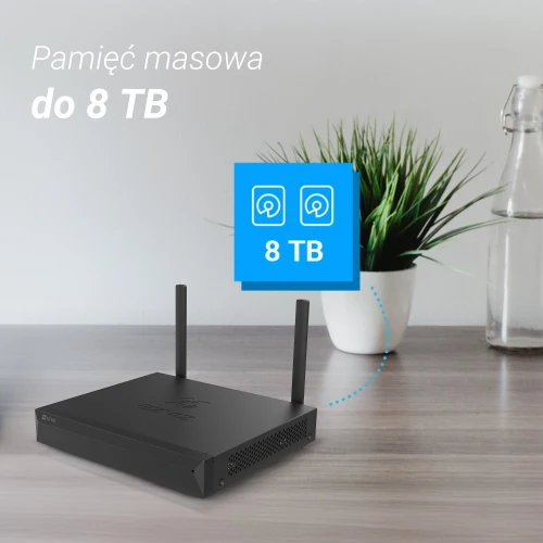 Na zdjęciu znajduje się czarny rejestrator IP Ezviz X5S-8W z dwiema antenami, umieszczony na drewnianym blacie. W tle widoczna jest zielona roślina w białej doniczce oraz szklana butelka, a po lewej stronie znajduje się napis "Pamięć masowa do 8 TB".