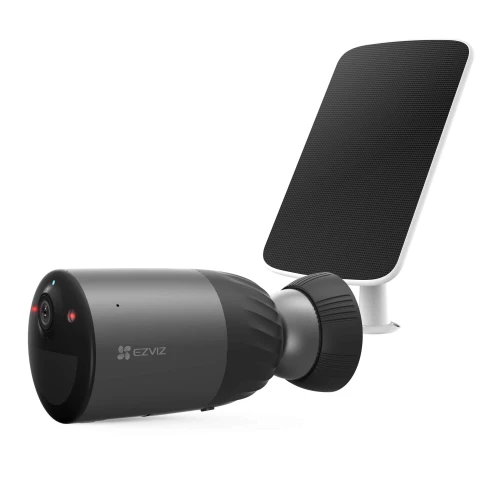 Na zdjęciu znajduje się czarna kamera bezprzewodowa z logo EZVIZ, obok której widoczny jest panel słoneczny. Kamera ma cylindryczny kształt i jest skierowana w lewą stronę, a panel słoneczny jest ustawiony pod kątem.