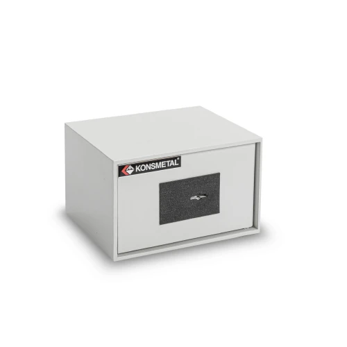 Na zdjęciu znajduje się prostokątny, szary sejf z czarnym zamkiem kluczowym na przedniej stronie. Na górze sejfu widnieje logo "Konsmetal".