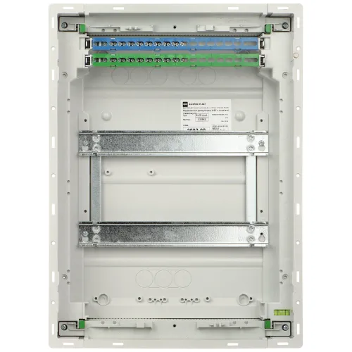 Zdjęcie przedstawia wnętrze białej obudowy elektrycznej z metalowymi szynami montażowymi i listwą zaciskową na górze. W środku widoczna jest etykieta z informacjami technicznymi.