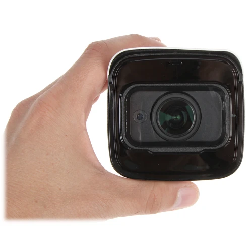 Na zdjęciu widać rękę trzymającą kamerę monitoringu z widocznym obiektywem skierowanym w stronę aparatu. Kamera ma kwadratowy kształt i czarną obudowę.