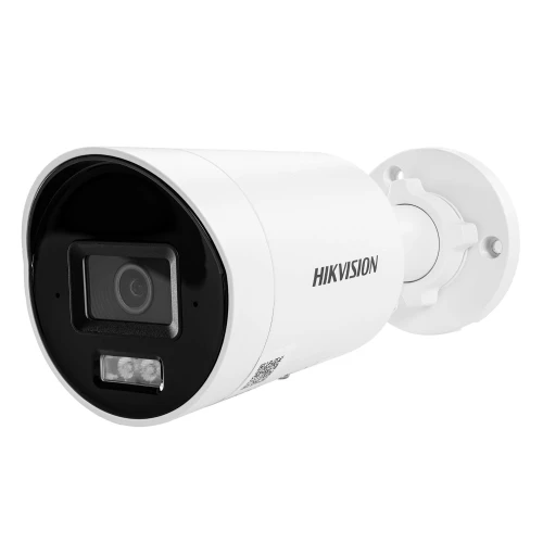 Na zdjęciu znajduje się biała kamera monitoringu marki Hikvision z czarnym frontem i obiektywem umieszczonym centralnie. Kamera jest zamontowana na białym uchwycie ściennym.