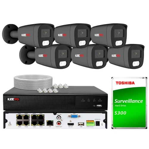 Na zdjęciu znajduje się zestaw do monitoringu, który obejmuje sześć kamer, rejestrator oraz dysk twardy Toshiba S300. W tle widoczne są również akcesoria, takie jak kable i złącza.