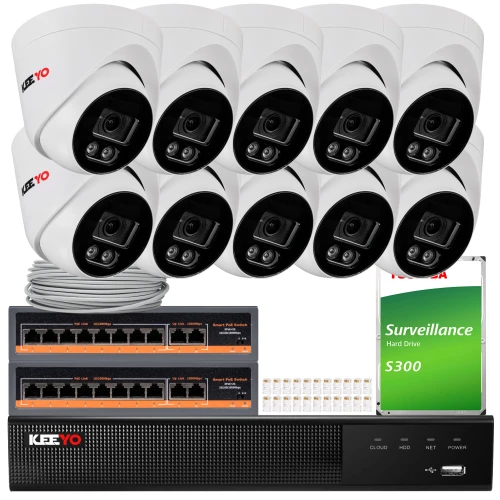 Na zdjęciu znajduje się zestaw do monitoringu, który obejmuje osiem białych kamer, dwa czarne rejestratory, dysk twardy oraz kable i akcesoria montażowe. Kamery mają czarno-białą kolorystykę z widocznym logo "KEEYO".