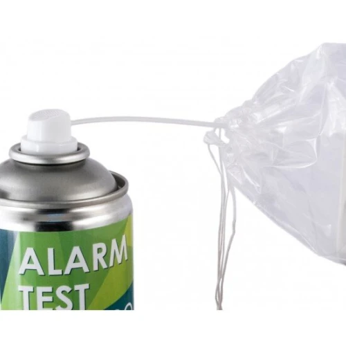 Na zdjęciu znajduje się puszka z aerozolem do testowania alarmów, z widocznym napisem "ALARM TEST". Obok puszki znajduje się przezroczysta plastikowa osłona z przewodem.